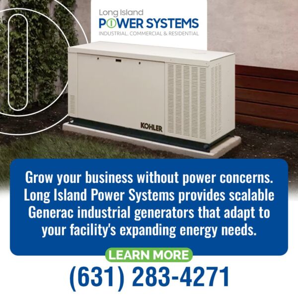A white Kohler industrial backup generator unit sits outdoors on a concrete pad next to a building and greenery.