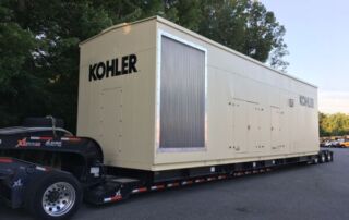 Safety First: Essential Generator Safety Tips for Businesses and Facilities Relying on Industrial Generators | 9 | Long Island Power Systems A large Kohler generator secured on a specialized trailer for transport, with trees in the background.